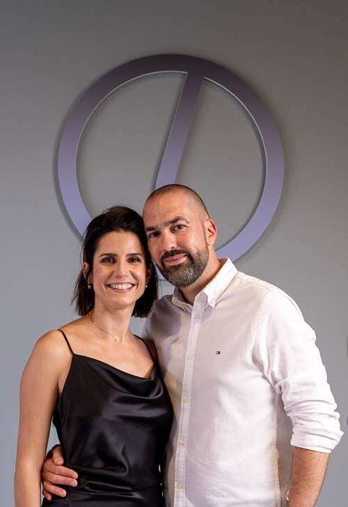 Portrait de Pierre et Delphine Loubat, fondateurs de LOUBAT AUTOMOBILE, posant avec élégance devant le logo de leur entreprise. Un duo passionné et complice, dédié à offrir une expérience automobile haut de gamme personnalisée et authentique